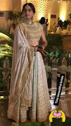 a woman in a white and gold lehenga is posing for the camera with her hands on her hips