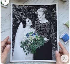 two hands holding up a photo of an older woman and young man on their wedding day