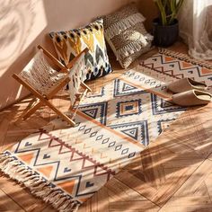 a wooden chair sitting on top of a hard wood floor next to pillows and rugs