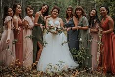 a group of women standing next to each other in front of trees and bushes with flowers