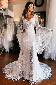 a woman in a white wedding dress standing on a wooden floor with her arms out