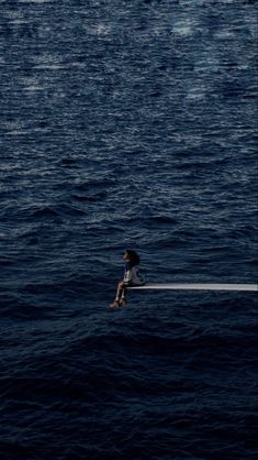 a person sitting on top of a boat in the ocean