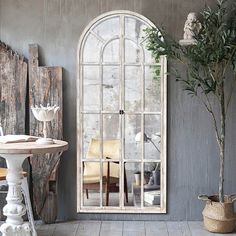 a room with a table, chairs and a large arched glass window on the wall