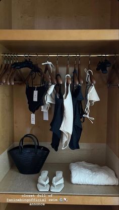 a closet with clothes and shoes hanging on the rack, next to a black bag