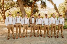 a group of men standing next to each other wearing sunglasses and bow ties in front of trees