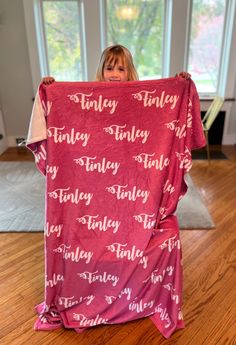 a woman holding up a red blanket with words on it