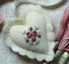 a heart shaped brooch with flowers on it next to some thread and yarns