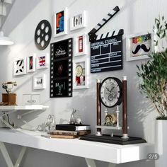 a white desk topped with a clock next to a plant and movie slates on the wall