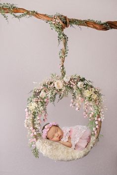 a baby girl is sleeping in a flowered hammock hanging from a twig