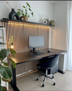 a desk with a computer on it in front of a wall mounted plant and potted plants