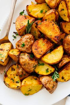 a white plate topped with roasted potatoes and herbs