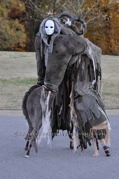 two people dressed up in costumes standing next to each other on the street with trees and grass behind them