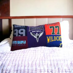 a bed topped with pillows covered in different sports jerseys on it's sides and an attached headboard