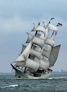 a large white sail boat sailing in the ocean