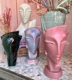 three vases are sitting on a table in front of a mirror, one is pink and the other is blue