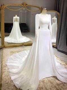 a white wedding dress on display in front of a mirror with other dresses behind it