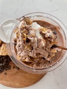 a bowl filled with chocolate pudding and whipped cream on top of a wooden board next to crackers