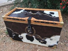 an old trunk with cow hides on the bottom and leather trimming around it