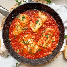 a skillet filled with meat covered in sauce and garnished with parsley