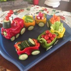 there are many vegetables in the shape of a train on a blue platter with cucumbers and radishes