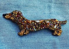 a beaded dachshund brooch sitting on blue fabric