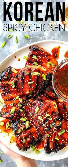 korean spicy chicken on a white plate with dipping sauce in the middle and two hands holding it