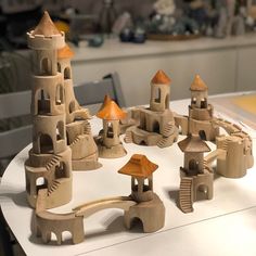 a group of wooden toy houses sitting on top of a white table next to each other