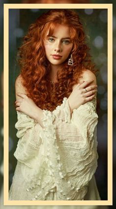 a woman with long red hair is posing for a photo wearing a white dress and holding her arms on her chest