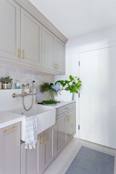 a kitchen with white cabinets and green plants on the counter top, along with a sink