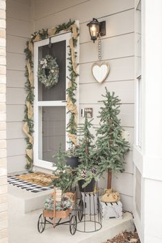 the front porch is decorated for christmas with wreaths and pine trees on display outside