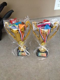 two trophies sitting on top of each other in plastic cups with ribbons around the edges