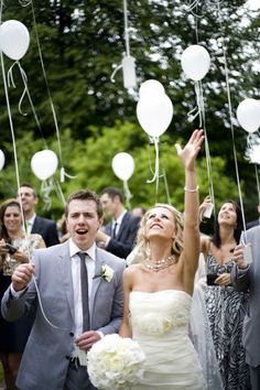 a bride and groom are surrounded by confetti and balloons as they walk down the aisle