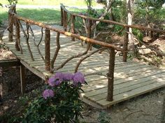 a small wooden bridge with purple flowers on it