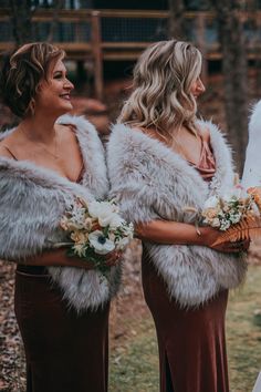 two bridesmaids wearing fur stoles and holding bouquets