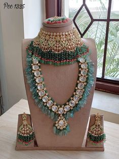 an elaborate necklace and matching earring set on display in front of a large window