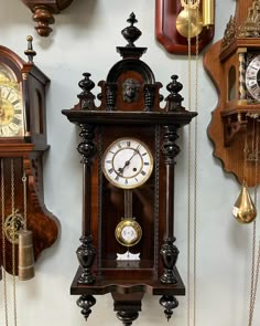 several clocks are hanging on the wall with chains attached to each clock and pendulums