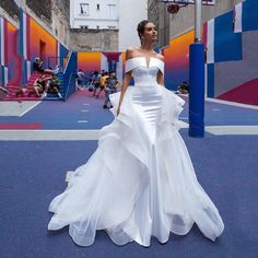 a woman in a white wedding dress standing on a basketball court with her hands behind her back