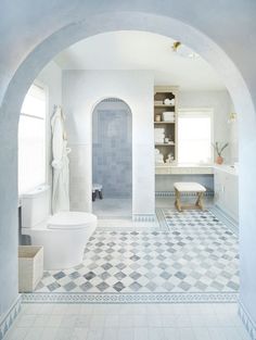 an arched doorway leads into a bathroom with blue and white tiles on the flooring