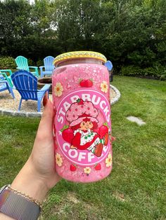 a person holding up a pink cup with an image of a cartoon character on it