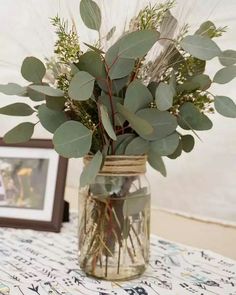 a vase filled with greenery on top of a table