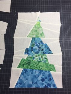 a piece of paper is cut up to look like a christmas tree with blue and green trees on it