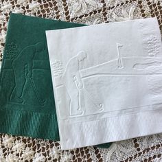 two green and white napkins sitting on top of a doily