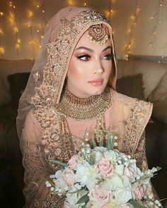 a woman wearing a bridal veil and holding a bouquet of flowers in front of her face