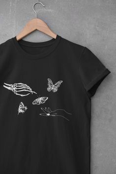 * Our Creation of Adam T-shirt and Skeleton Hand with Butterflies which is inspired by Michelangelo is great fit for both trendy and casual look.  * This style is unisex, size down for more fit style or size up for more oversized look. * As our t-shirts are printed as customer orders them, we cannot accept returns for change of mind - thank you for understanding! -SHIPPING- * We print our shirts as customers order them. Please allow 2-7 business days. * Please allow 2-5 business days for shippin Groovy Halloween, Gods Hand, Butterfly Shirts, Skeleton Shirt, Skeleton Hand, Aesthetic Shirts, Retro Tee, Skeleton Hands, Halloween Skeleton