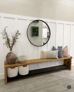 a wooden bench sitting next to a mirror and vases on top of each other