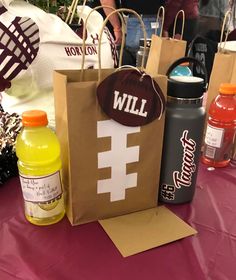 paper bags with sports items on them are sitting on a purple tablecloth covered table