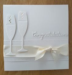 congratulations card with two champagne glasses and ribbon on the front, in white paper that says congratulations