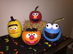 three pumpkins decorated to look like sesame street characters