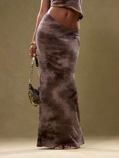 a woman in a long skirt holding a purse