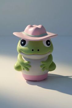 a frog wearing a pink hat sitting on top of a white table next to a wall